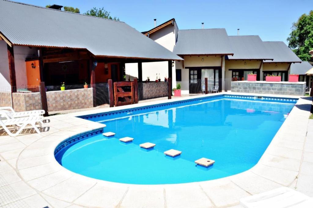 a swimming pool with chairs and a house at Los Alamos in Villa General Belgrano