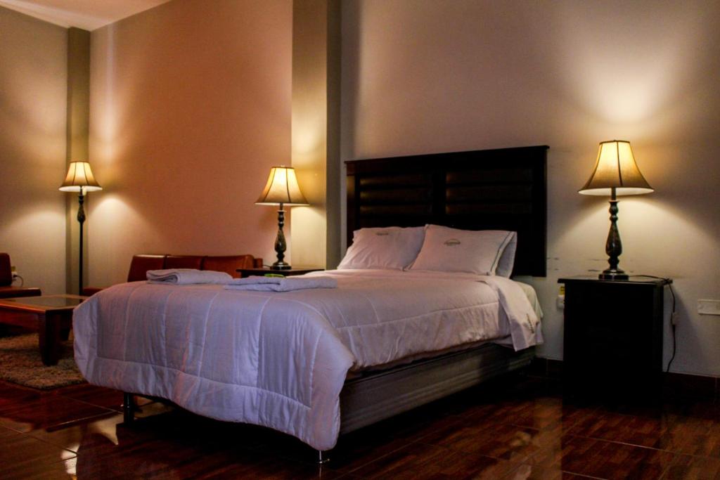 a bedroom with a large bed with two lamps at Hotel Los andes Suite Cajamarca in Cajamarca