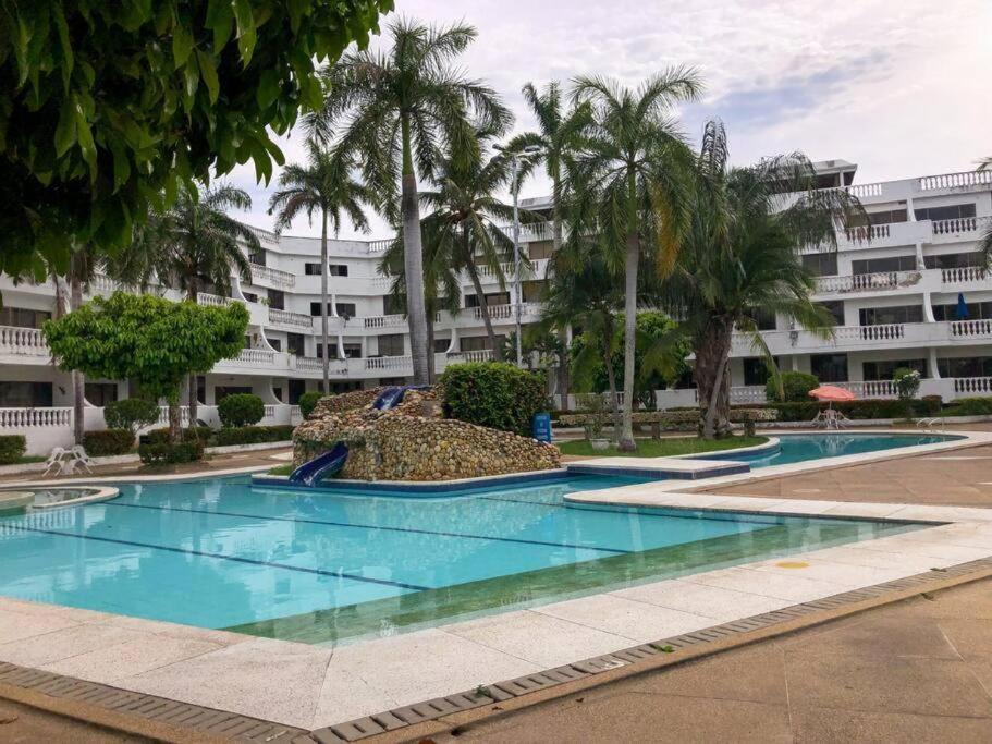 un complejo con 2 piscinas con palmeras y un edificio en lujoso apartamento, en Ricaurte
