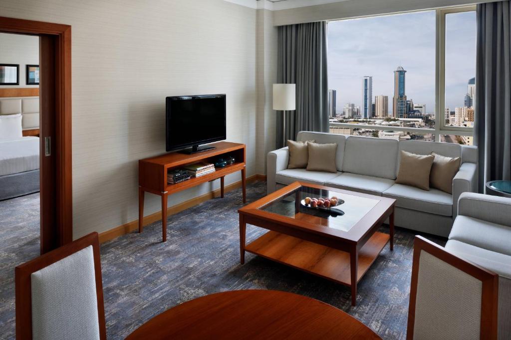 a living room with a couch and a tv at Courtyard By Marriott Kuwait City in Kuwait