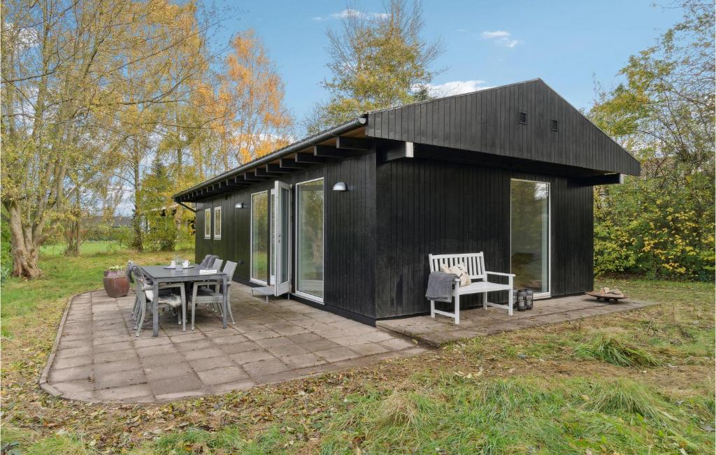 una casa negra con una mesa y sillas en un patio en Gorgeous Home In Kirke Hyllinge With Wifi, en Kirke-Hyllinge