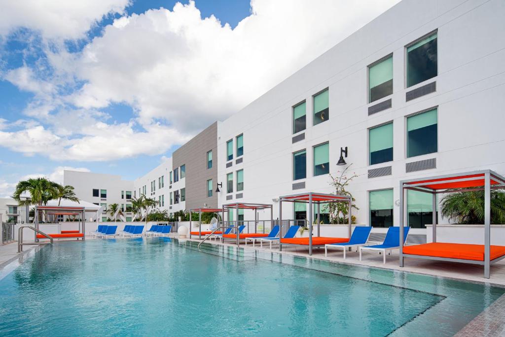 a swimming pool with blue and orange chairs and a building at Aloft Delray Beach in Delray Beach