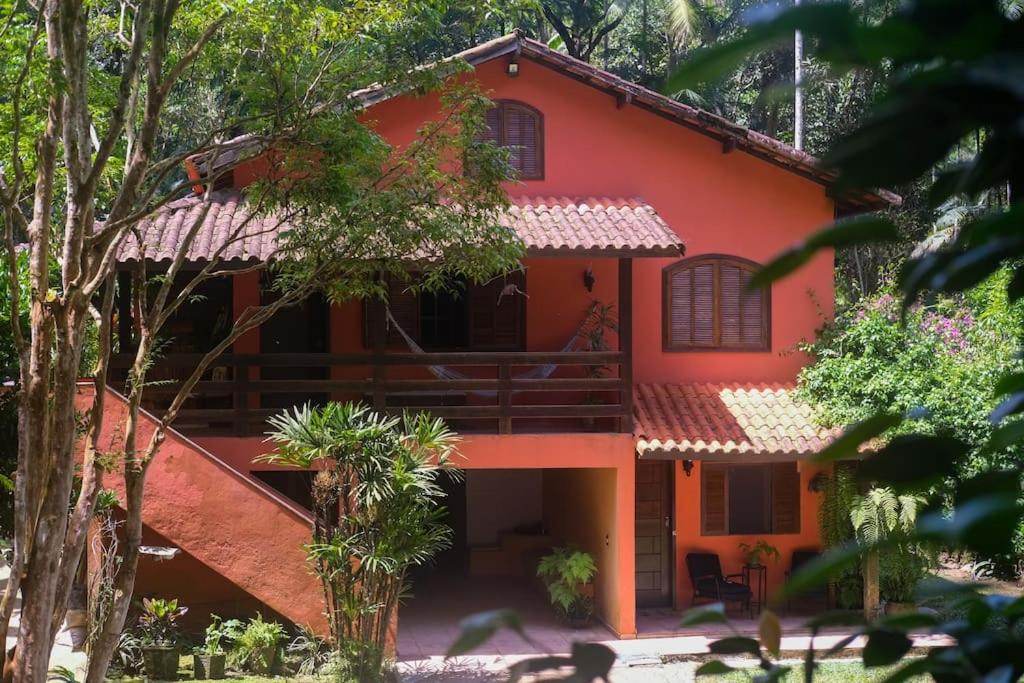 una casa roja con árboles delante de ella en Casa em penedo com cachoeira en Penedo