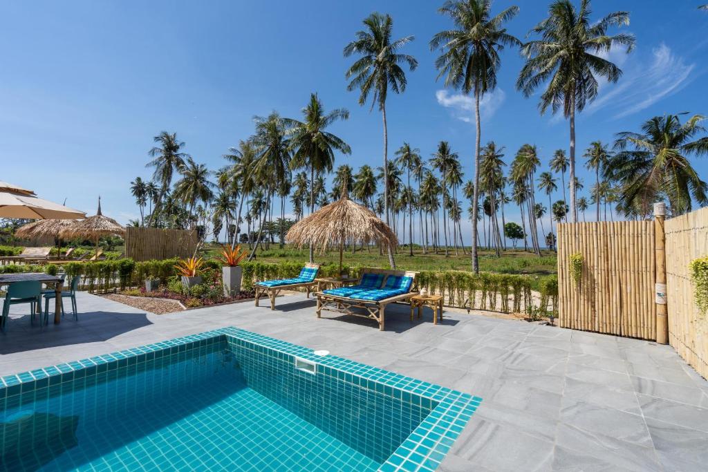 a swimming pool with a patio and palm trees at Manao Seaview Pool Villa 25 - 5 Mins Walk To The Beach in Ko Lanta