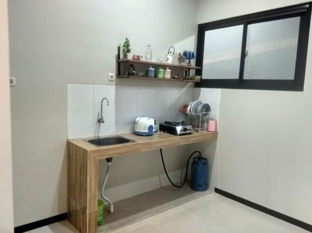 uma cozinha com um balcão com um lavatório e uma janela em Phoenix Guest House em Surabaya