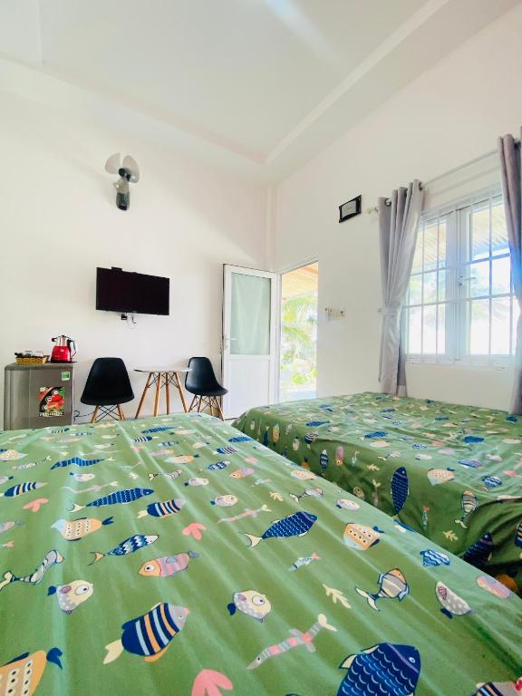 a bedroom with a bed with a green comforter with fish on it at Homestay BONO Mũi Né in Phan Thiet