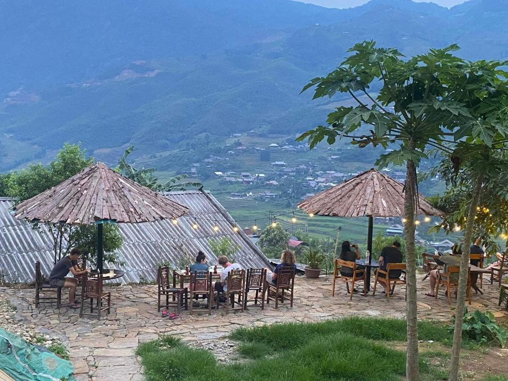 Hmong Sister House and Trekking في سابا: مجموعة من الناس يجلسون على الطاولات تحت المظلات