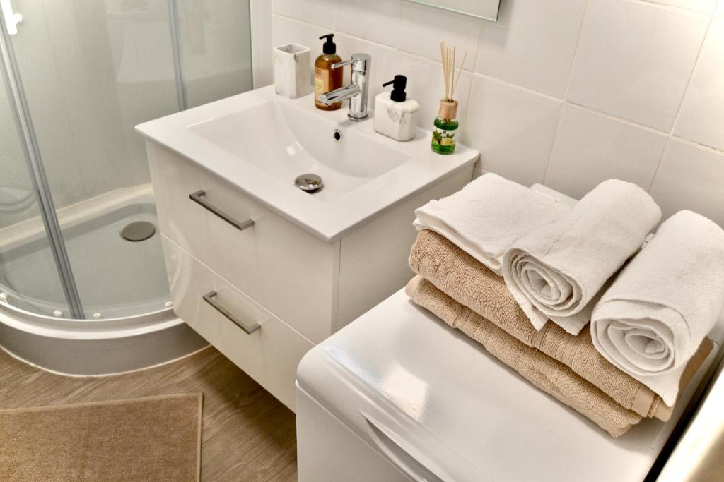 La salle de bains blanche est pourvue d'un lavabo et d'une douche. dans l'établissement Cocon Urbain, Centre Ville Quartier Vieux-Port - rue Paradis, Rénové, climatisé, 3pers, à Marseille
