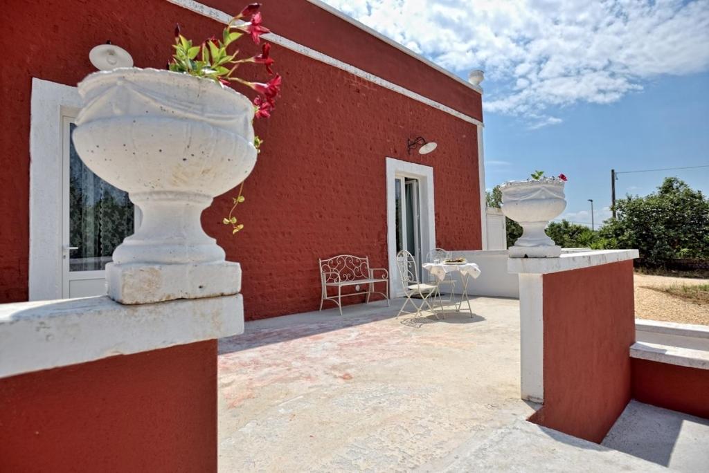 ein rotes Haus mit zwei großen weißen Vasen an der Wand in der Unterkunft Villa Giorgia in Monopoli