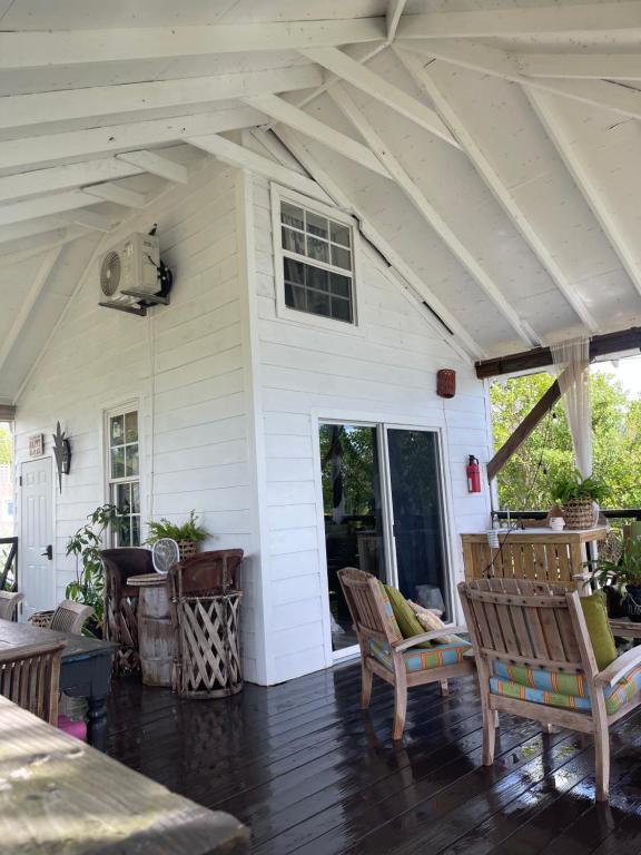 a white house with a porch with rocking chairs at Hidden Paradise - Cottage in Nassau