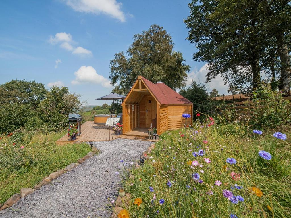 a small wooden cabin with a wooden walkway and flowers at Dol Y Mynydd the Mountain Meadow-qu7521 in Llangerniew
