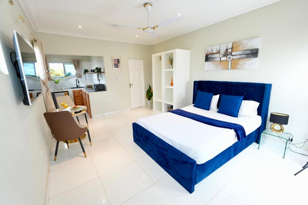 um quarto com uma cama azul e uma mesa em Lukas Garden Accra em Acra