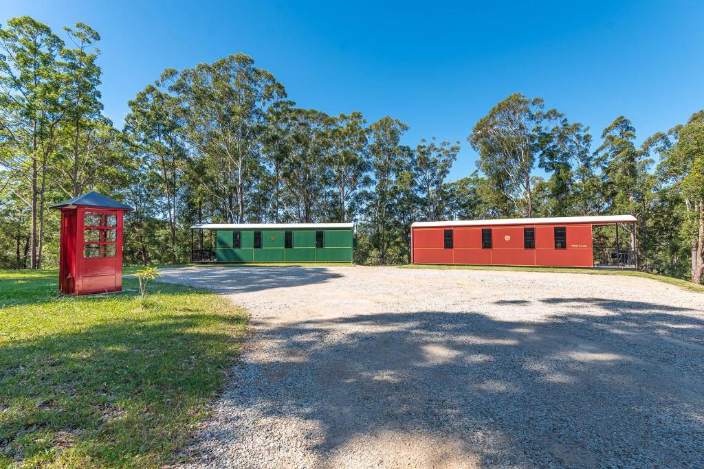 two red and green buildings in a field at Nambucca Valley Train Carriages in Nambucca