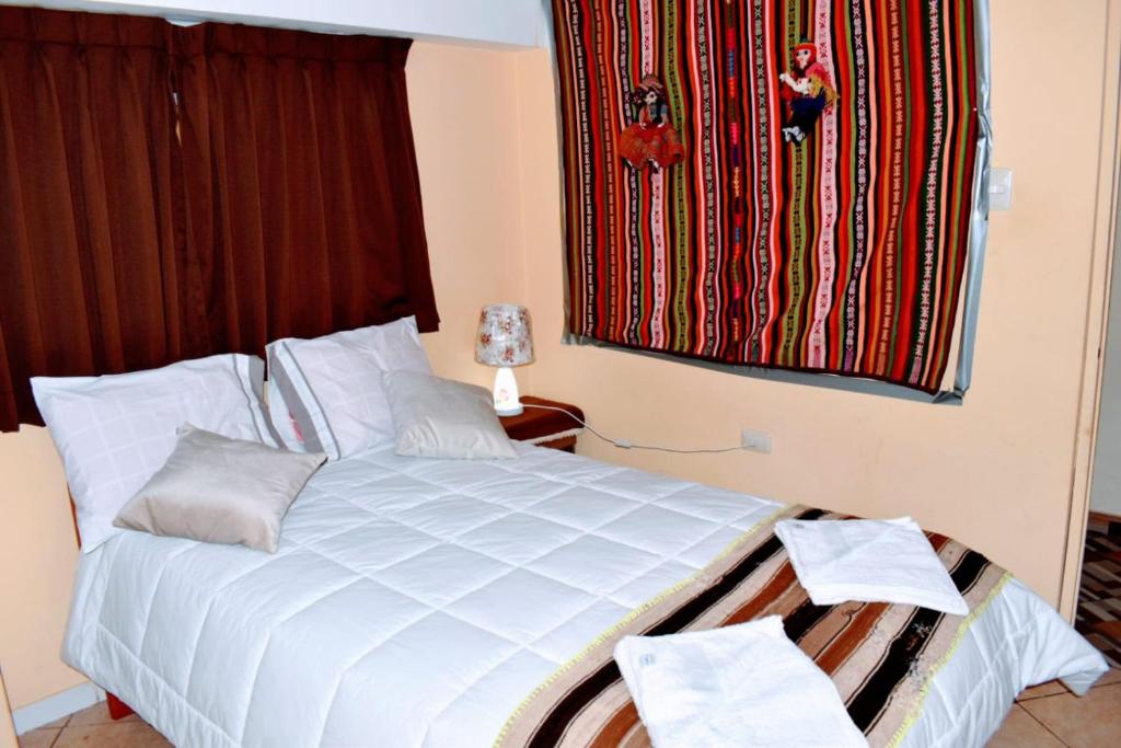 Un dormitorio con una gran cama blanca y una ventana en Cusqueñita 3 en Cuzco