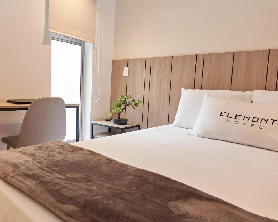 een slaapkamer met een bed en een bureau met een stoel bij Elemont Hotel in Medellín