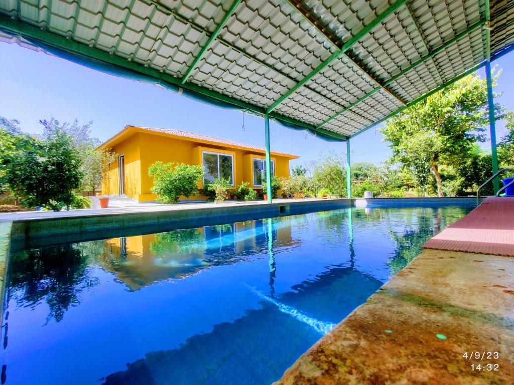 a swimming pool in front of a house at GiriSadan Organic Farm Retreat & Botanical Forest in Jaipur