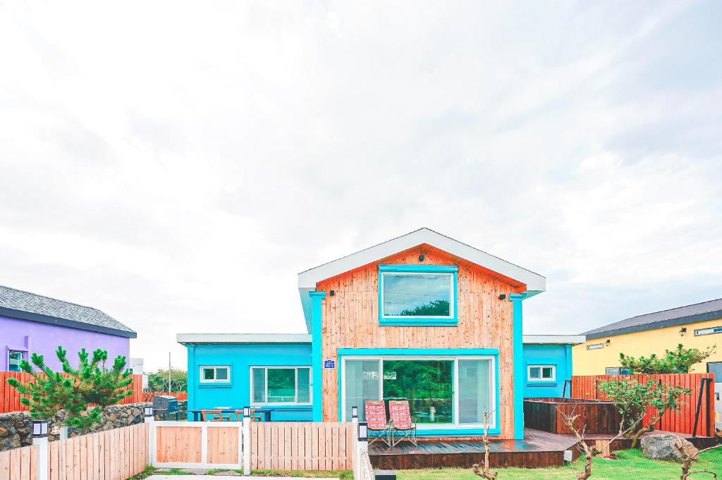 uma casa colorida com uma cerca em frente em Jeju Love Stay Mint em Jeju