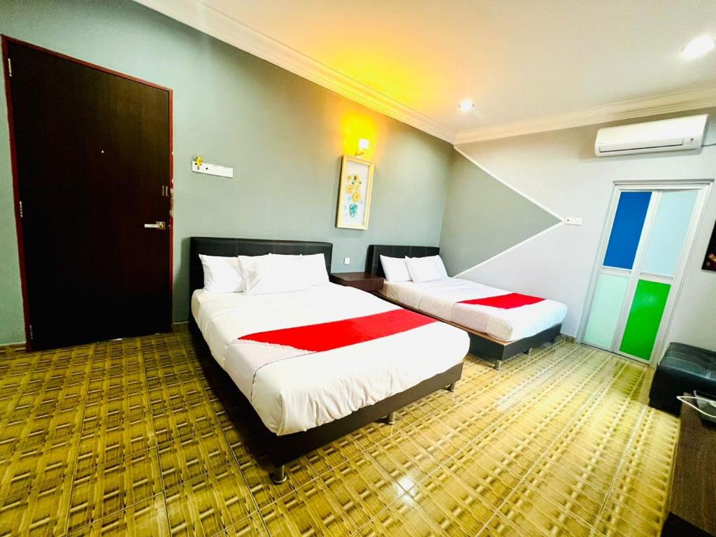 a hotel room with two beds and a door at DAILY INN HOTEL in Mersing