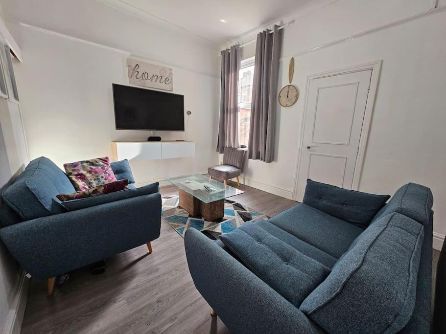 a living room with two blue couches and a tv at Cheerful Home near Preston train station & Uclan in Preston
