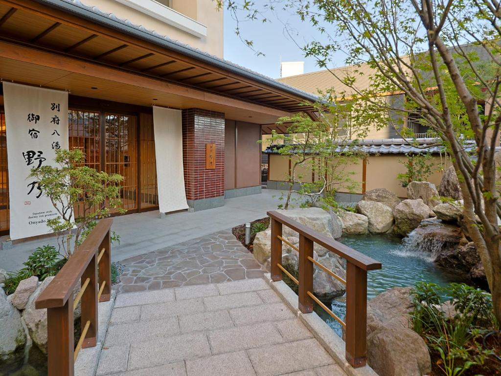 un jardín con un puente y un estanque frente a un edificio en Beppu Hatto Onyado Nono Beppu en Beppu