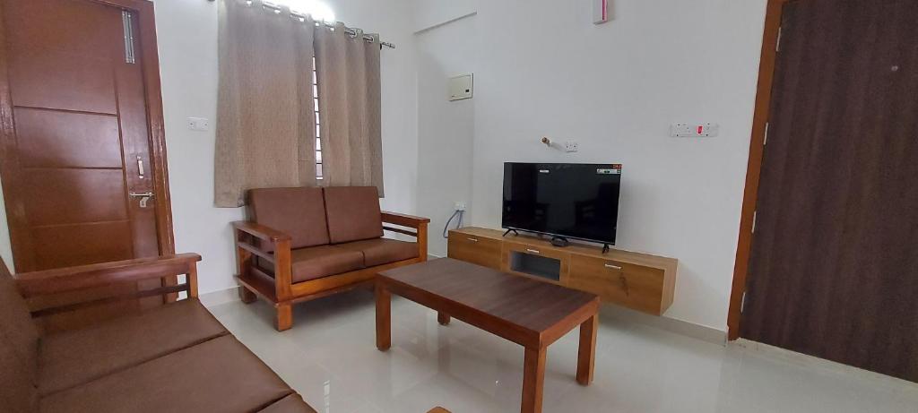 sala de estar con sofá, silla y TV en Tranquil Serviced Apartments - Sarjapur, en Bangalore