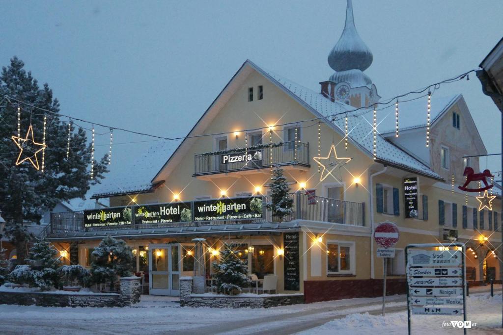 um edifício com luzes de Natal sobre ele na neve em Hotel Wintergarten em Schladming