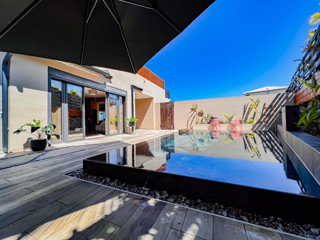 a house with a swimming pool and an umbrella at Résidence Daniza in Saint-Pierre