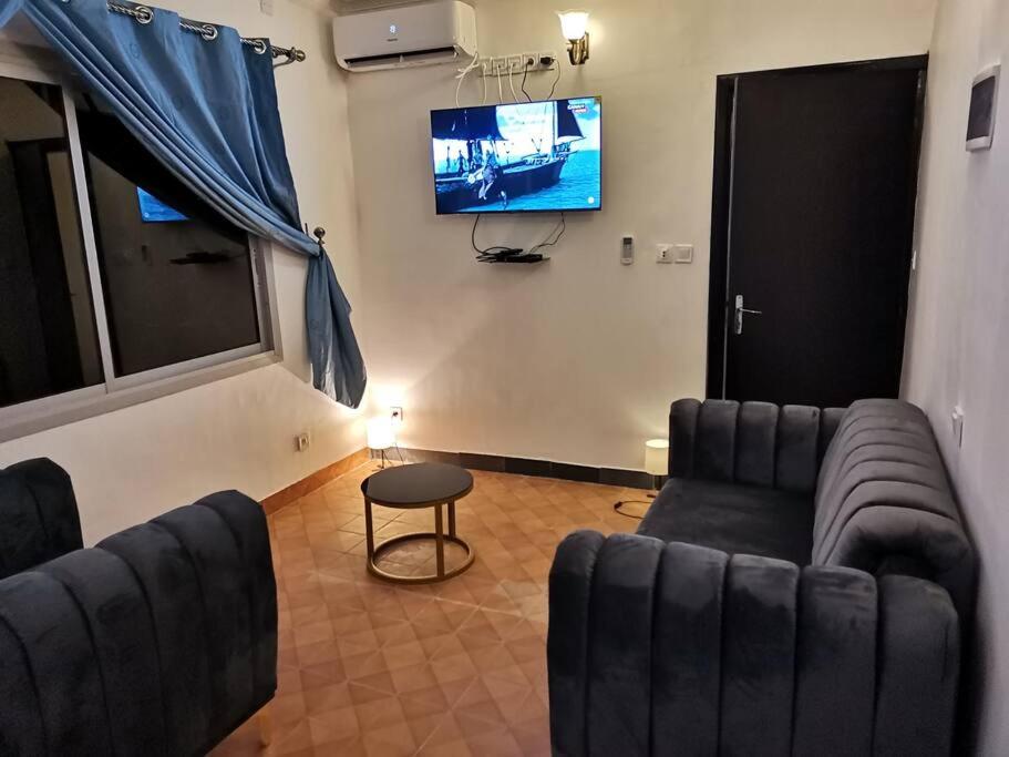a living room with two couches and a flat screen tv at Charmant,bien localisé et lumineux Appartement F2M/401A in Douala