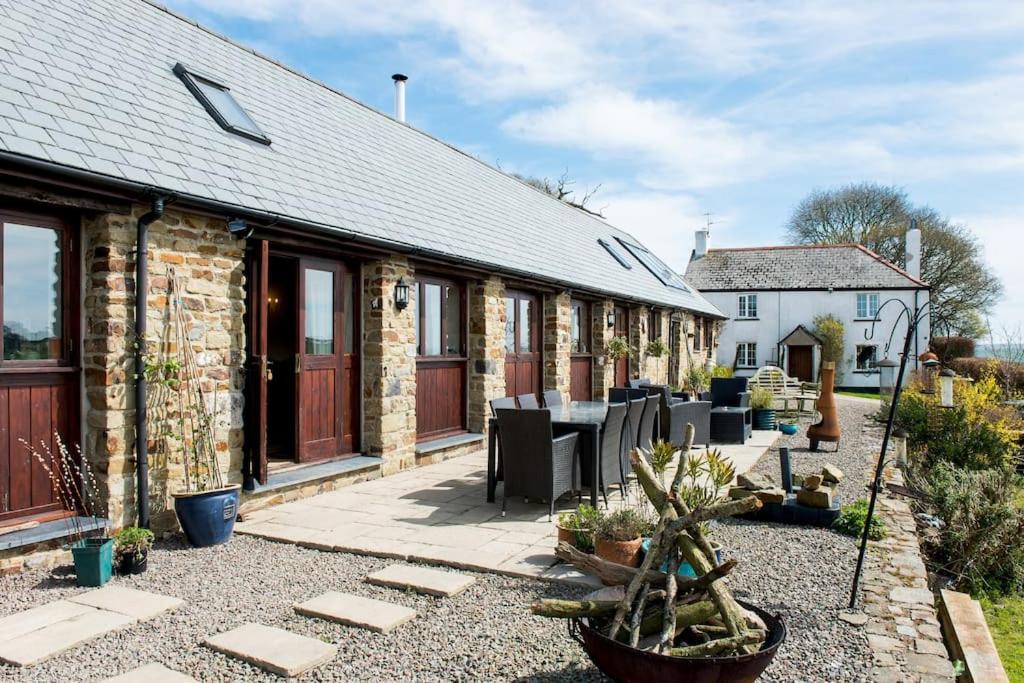 a stone cottage with a table and chairs in a yard at Unique Rural Stone dog friendly Barn Conversion in Okehampton
