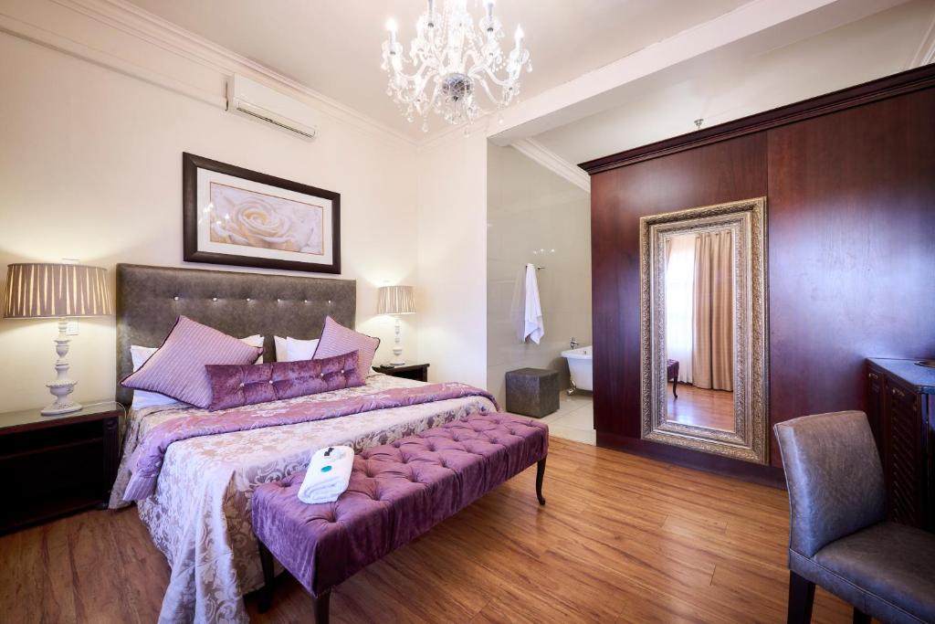 a bedroom with a large bed with a purple bedspread at Postmasburg d Olive Rose Boutique Hotel in Postmasburg