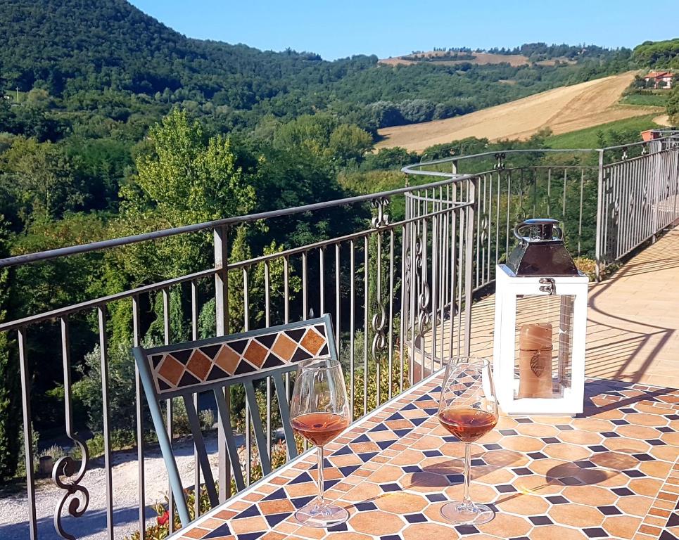 two glasses of wine sitting on a table on a balcony at GLI ALBERI apartment with view in Montepulciano