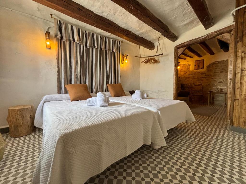 a bedroom with two beds with white sheets at Alojamiento Alberquina in Iznatoraf