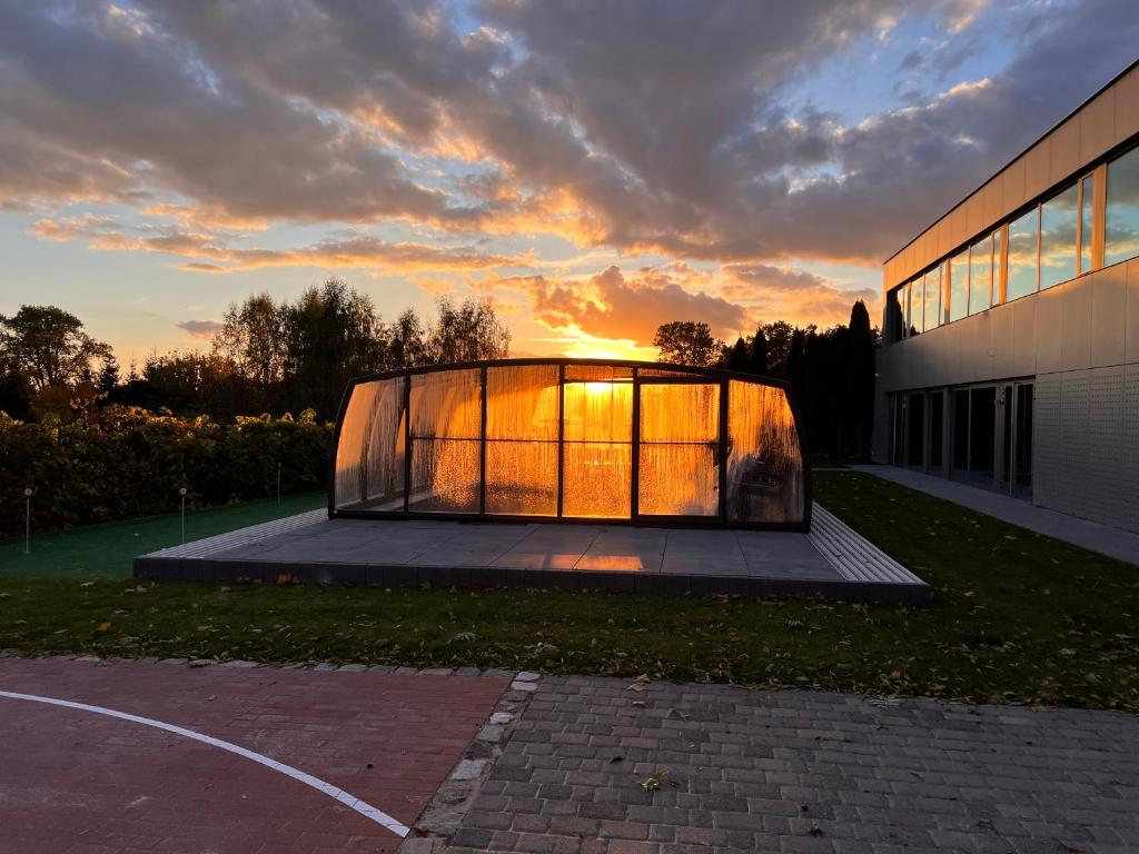 une maison en verre avec un coucher de soleil en arrière-plan dans l'établissement LedowoHouse Industrial Style kids friendly, à Lędowo