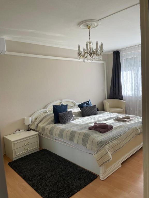 a bedroom with a large white bed with a chandelier at Bemma Apartman in Budapest