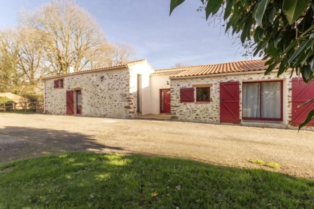 una casa con puertas rojas y una entrada de grava en Le Refuge d'Aglaé en Legé