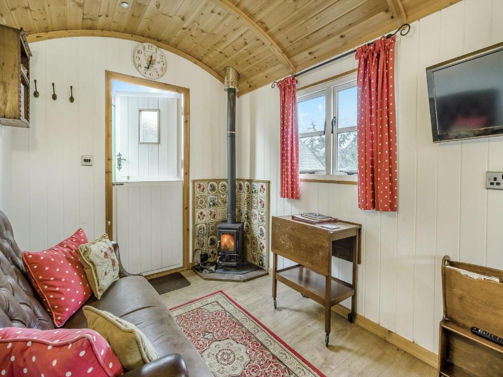 a living room with a couch and a fireplace at Shepherds Hut - Uk45529 in Buildwas
