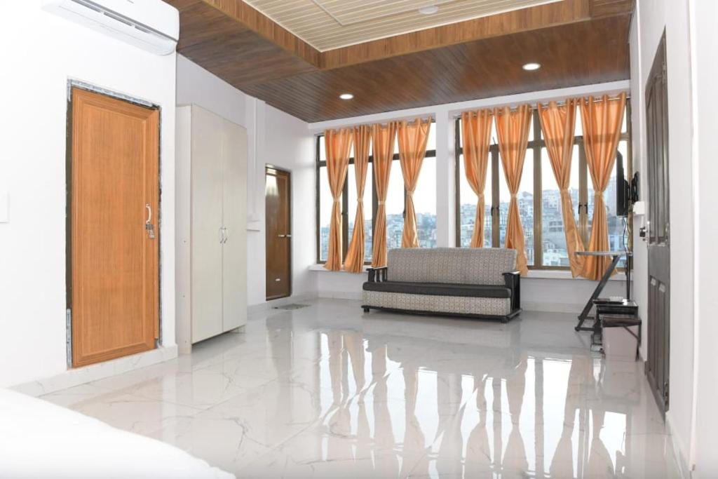 ein Wohnzimmer mit einem Sofa und großen Fenstern in der Unterkunft THE LUSHAI INN in Aizawl