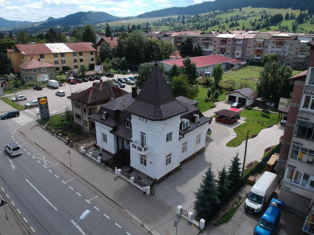 una grande casa bianca con un tetto nero su una strada cittadina di Villa Coca a Câmpulung Moldovenesc