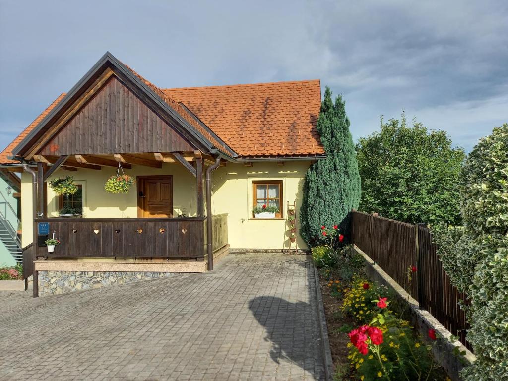 una pequeña casa amarilla con una valla y flores en Kuća Za Odmor Barbara, en Donja Stubica