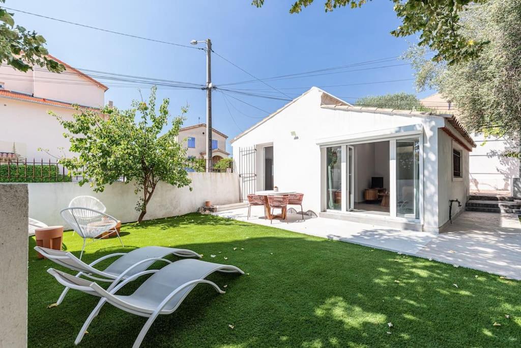 a lawn with chairs and a table in a yard at Maisonnette à 400m de la Plage in Villeneuve-Loubet