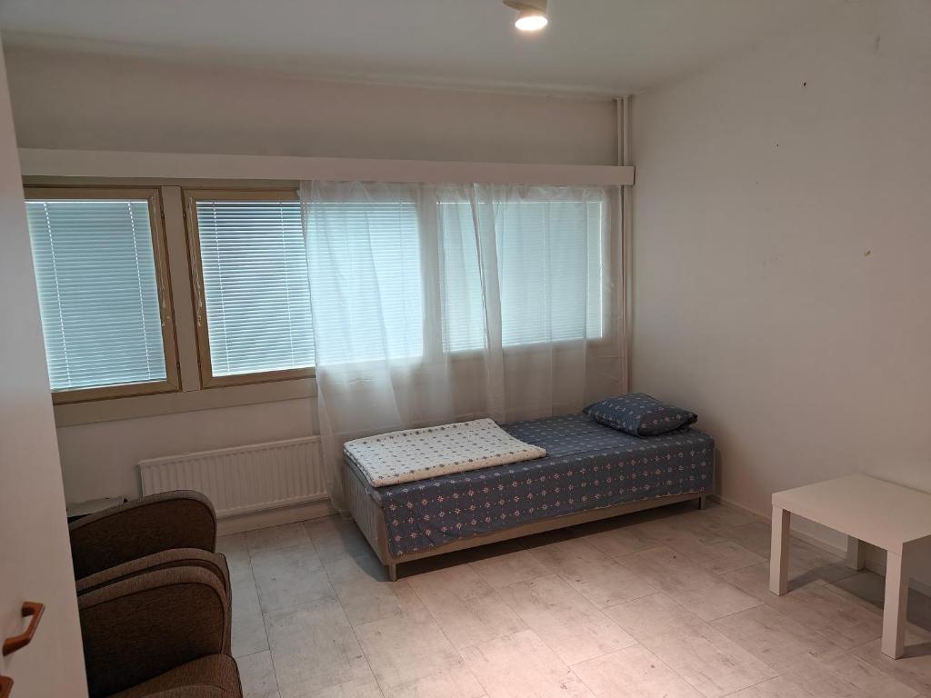 um pequeno quarto com uma cama e duas janelas em Heaven Hostel em Turku