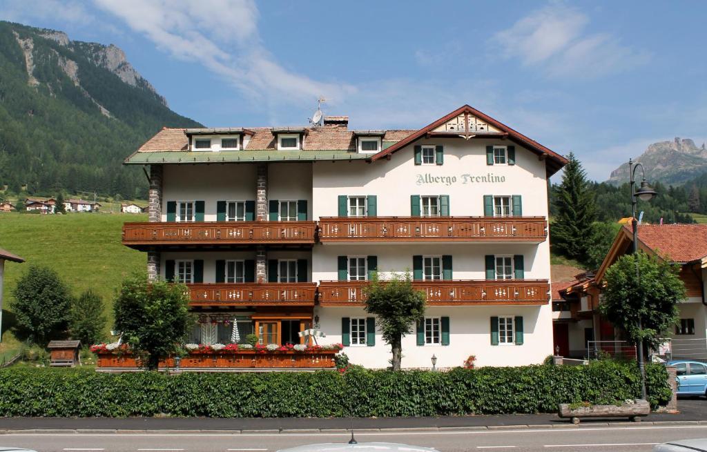 a large white building on a hill with a mountain at Albergo Trentino in Moena