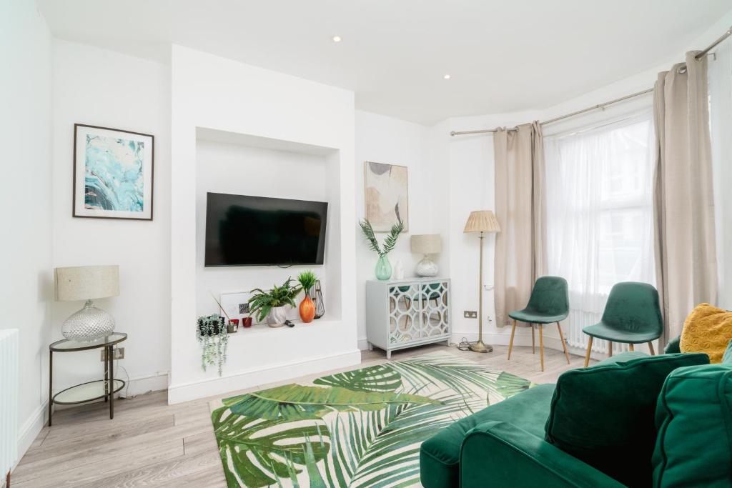 a living room with a green couch and a tv at Modern 2 bed apartment close to Westfield Stratford mall with garden in London