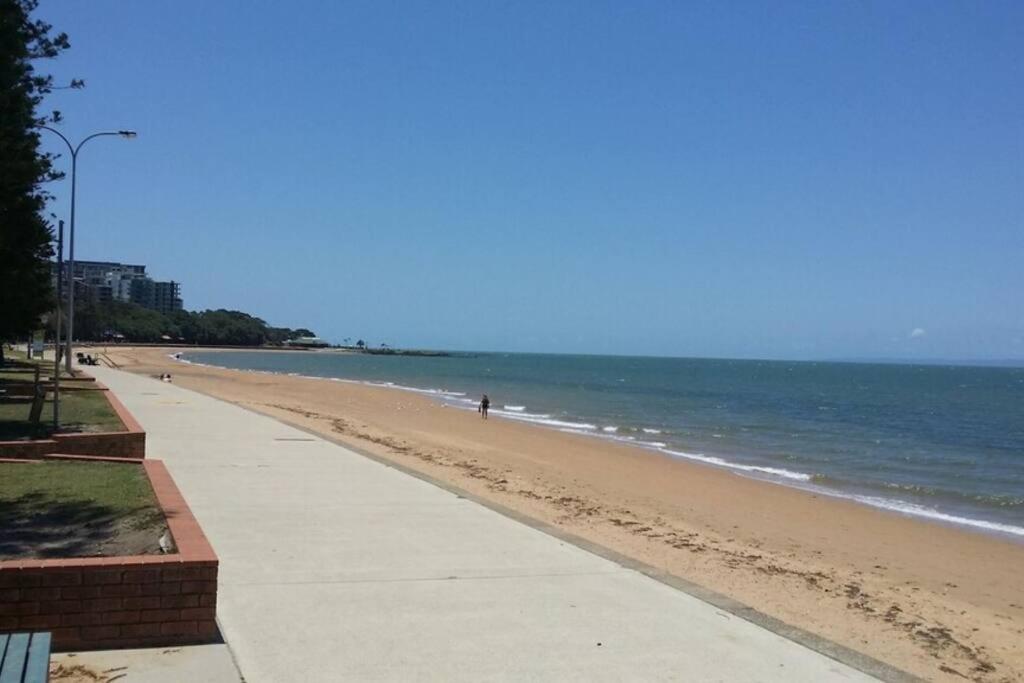 a beach with a person walking on the beach at Beach Pad Private Town house Sea Views Dual living 5 Beds in Redcliffe
