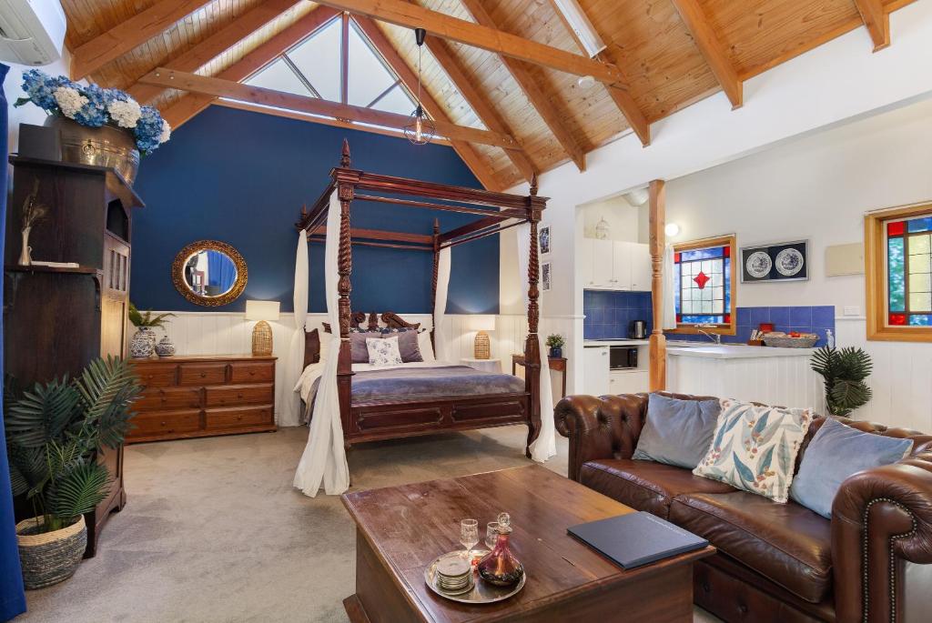 un soggiorno con un letto e un divano di Bluebell Cottage Gembrook - Heated Spa & Wood Fireplace a Gembrook