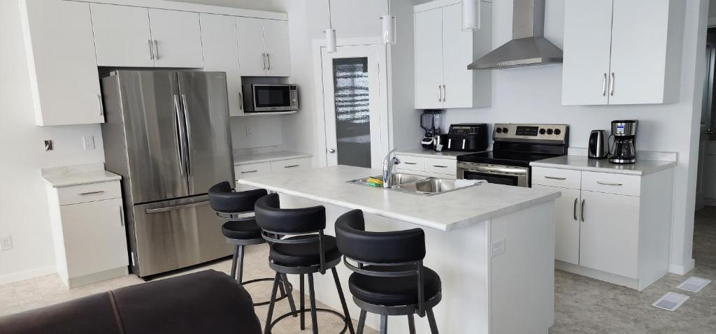 a kitchen with white cabinets and a counter with bar stools at Chesskings Suites - Polo-Park - 2 Bedrooms - Executive in Winnipeg