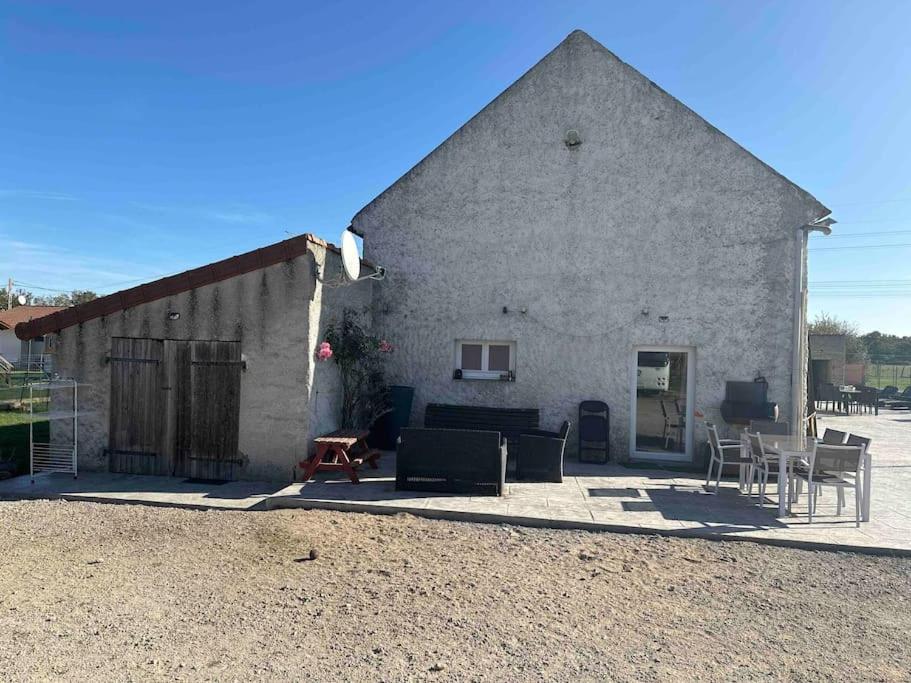 un grand bâtiment en briques avec des chaises et une table dans l'établissement Rez de maison jardin appart, à Saint-Pont