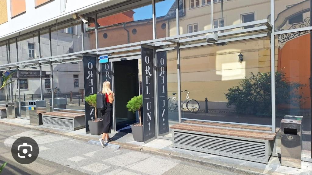 Una mujer saliendo por la ventana de una tienda en Hotel Orel en Maribor