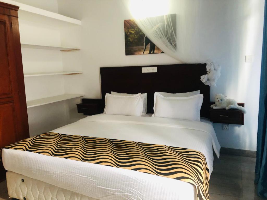 1 dormitorio con 1 cama con edredón blanco y negro en Ocean Pearl Cottage, en Ahungalla