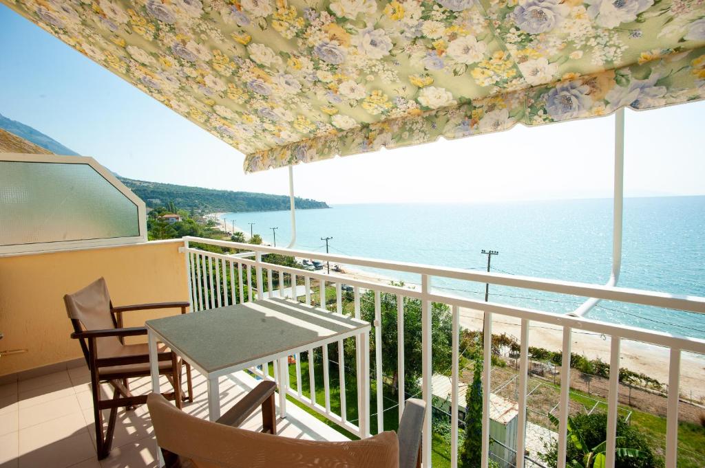 a balcony with a table and chairs and the ocean at Rosa's Beach Studios in Lourdhata